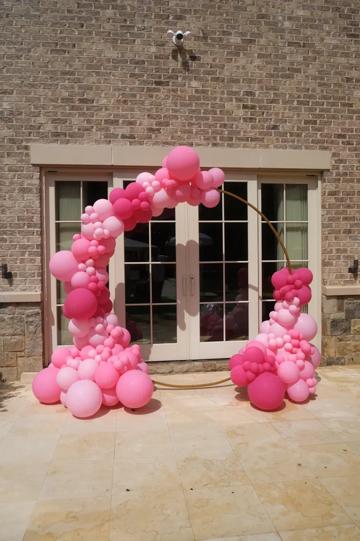 Soft pink balloons arranged around a gold circle